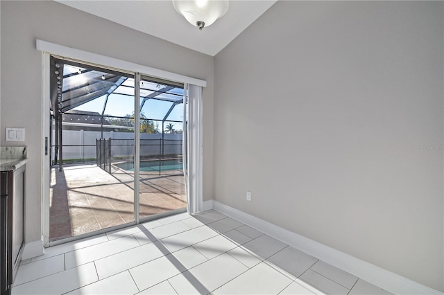 spare room featuring vaulted ceiling, light tile patterned floors, baseboards, and a sunroom