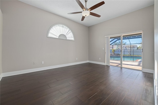 spare room featuring a ceiling fan, baseboards, and dark wood-style flooring