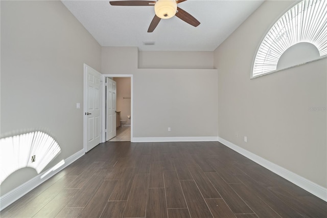 empty room with visible vents, baseboards, dark wood-type flooring, and ceiling fan