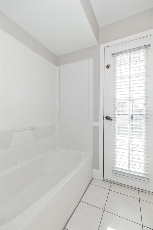 bathroom with tile patterned floors, a wealth of natural light, and a tub to relax in