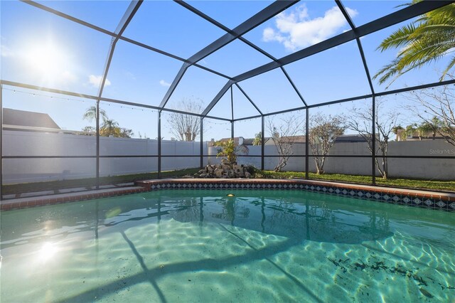 view of pool featuring glass enclosure, a fenced backyard, and a fenced in pool