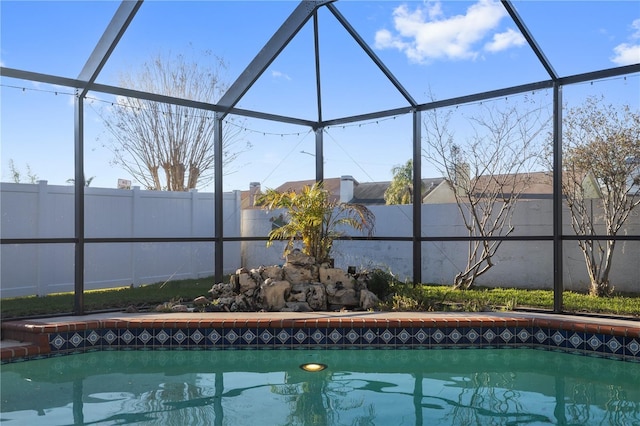 view of swimming pool with glass enclosure, a fenced backyard, and a fenced in pool