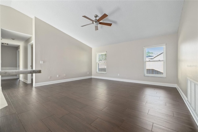 empty room featuring vaulted ceiling, plenty of natural light, and dark wood-type flooring