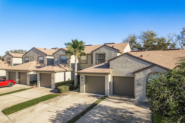 multi unit property with a garage, concrete driveway, roof with shingles, a residential view, and stucco siding