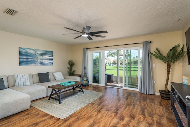 living area with a ceiling fan, visible vents, a textured ceiling, and wood finished floors