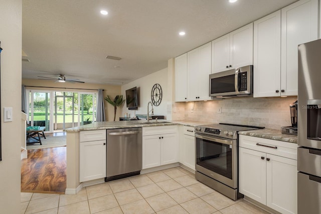 720 Earls Ct, Safety Harbor, FL 34695 - kitchen featuring backsplash, appliances with stainless steel finishes, white cabinetry, a sink, and a peninsula