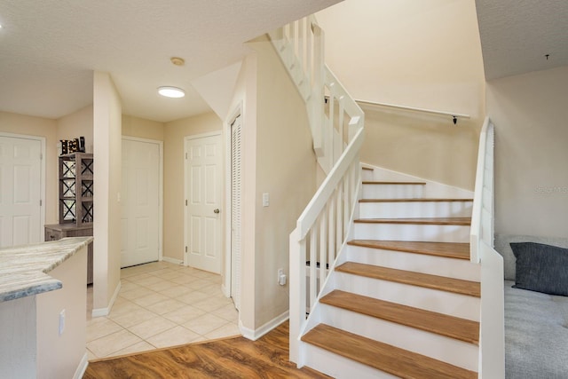 720 Earls Ct, Safety Harbor, FL 34695 - staircase with a textured ceiling, wood finished floors, and baseboards