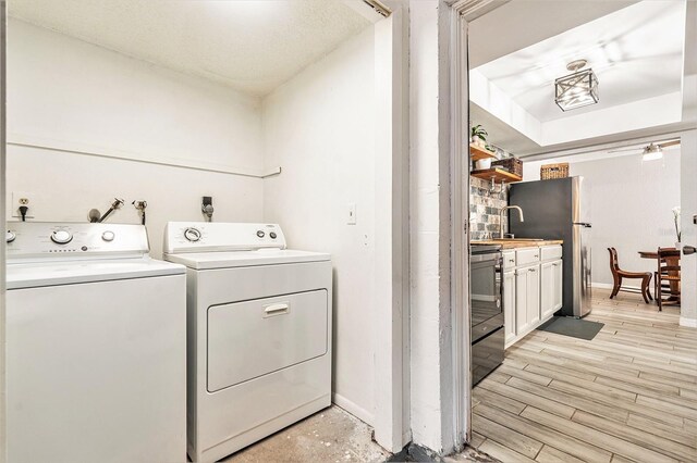 laundry room featuring washer and dryer, baseboards, light wood-style flooring, and laundry area