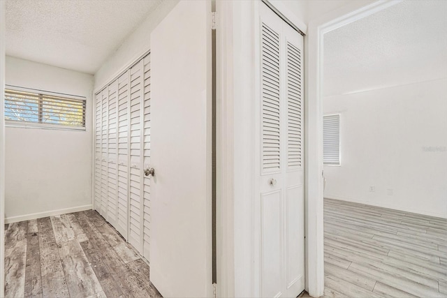 hallway with a textured ceiling and wood finished floors