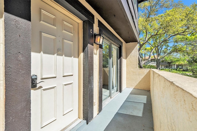 property entrance featuring stucco siding and a balcony