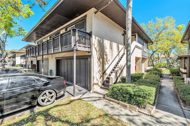 view of property exterior featuring stucco siding, stairs, and a garage