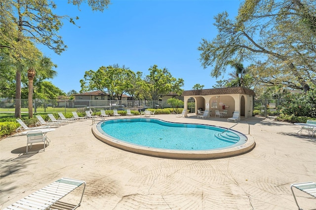 community pool with a patio and fence