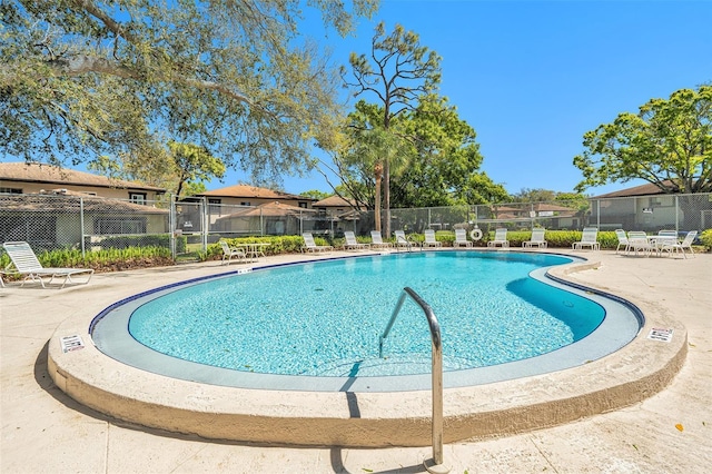 community pool with a patio, fence, and a residential view