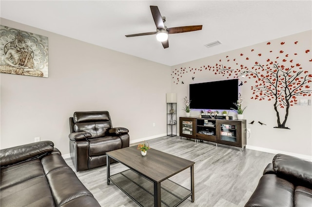 living area with light wood-style flooring, visible vents, baseboards, and a ceiling fan