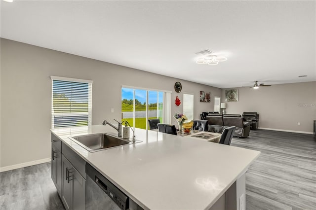 kitchen featuring light wood-type flooring, stainless steel dishwasher, visible vents, and a sink