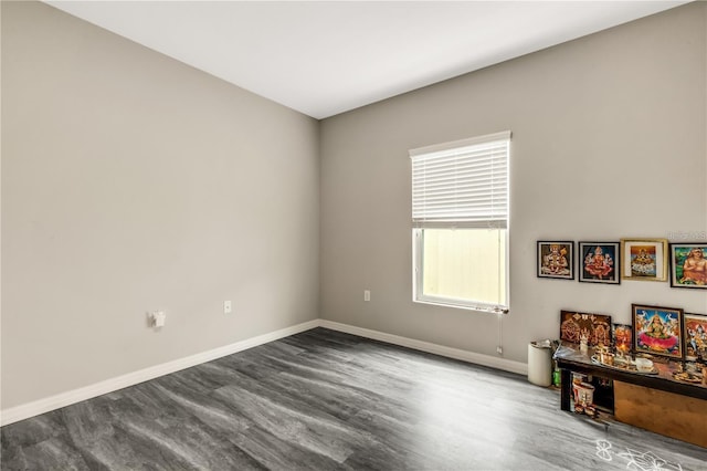 empty room with dark wood-style flooring and baseboards