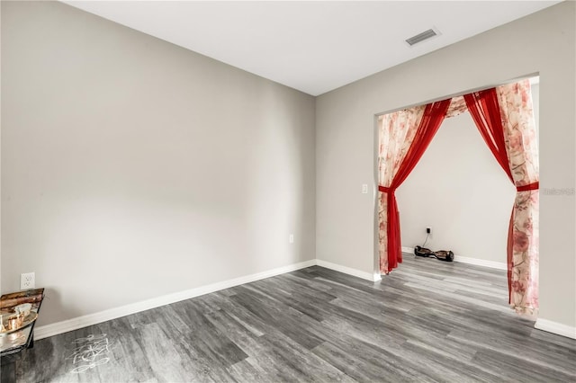 empty room featuring visible vents, baseboards, and wood finished floors