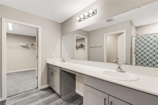 full bathroom with double vanity, a sink, visible vents, and a walk in closet