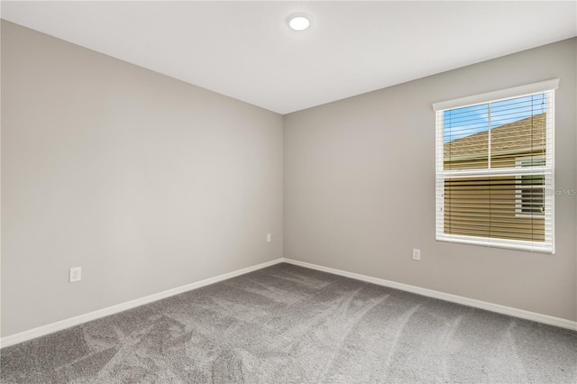 carpeted empty room featuring baseboards