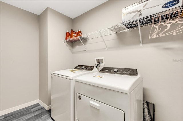 clothes washing area with laundry area, baseboards, separate washer and dryer, and wood finished floors