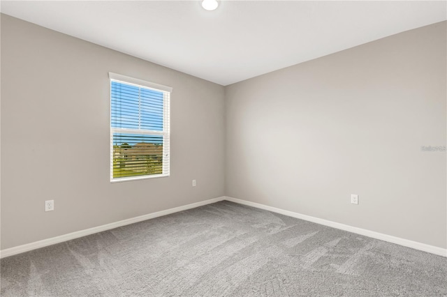 spare room featuring carpet flooring and baseboards