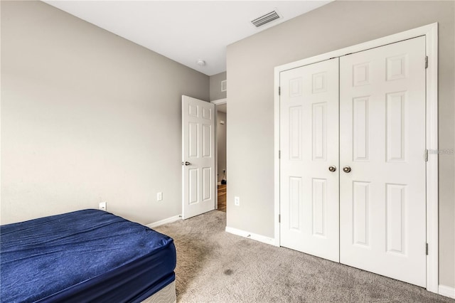 carpeted bedroom with a closet, visible vents, and baseboards