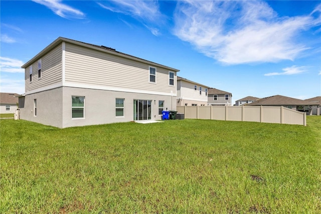 back of property featuring fence and a lawn