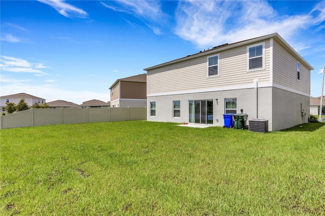 back of property featuring central AC unit, fence, and a lawn