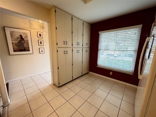 unfurnished bedroom with a closet, baseboards, and light tile patterned floors