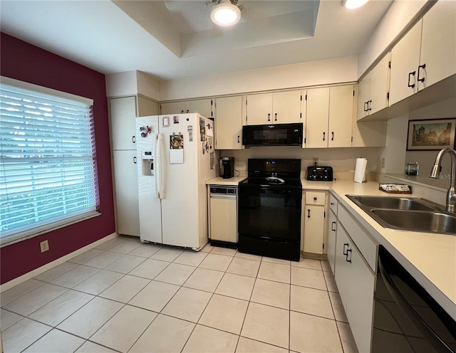 kitchen with a raised ceiling, ceiling fan, light countertops, black appliances, and a sink