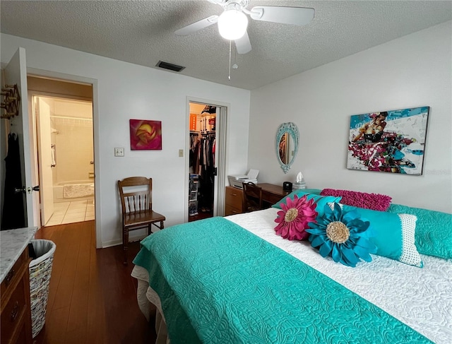 bedroom with visible vents, dark wood-style floors, a walk in closet, a textured ceiling, and a closet