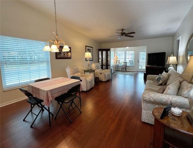 dining area featuring vaulted ceiling, dark wood-style flooring, ceiling fan with notable chandelier, and a textured ceiling