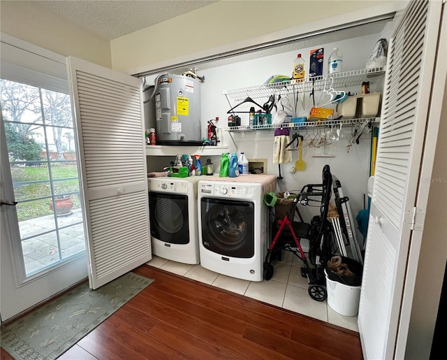 clothes washing area with laundry area, wood finished floors, electric water heater, washing machine and clothes dryer, and a textured ceiling