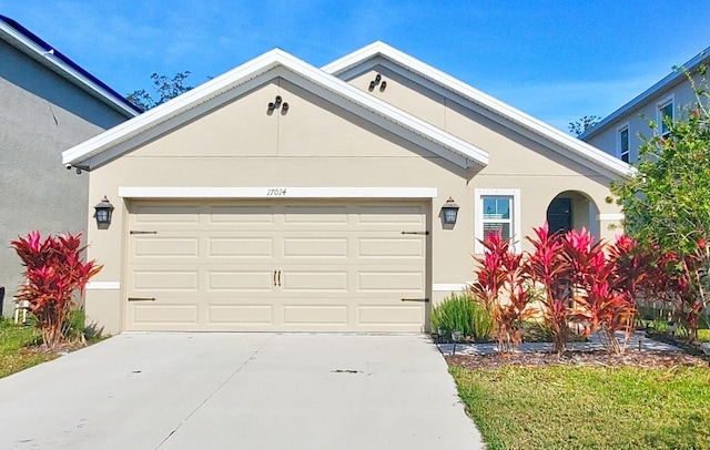 ranch-style home with driveway, an attached garage, and stucco siding