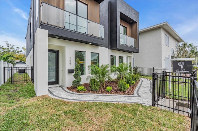 exterior space with a front yard, fence, and stucco siding