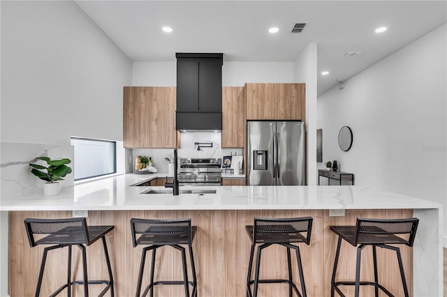 kitchen featuring visible vents, modern cabinets, appliances with stainless steel finishes, a peninsula, and custom exhaust hood