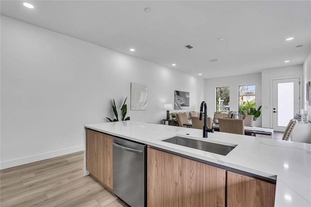 kitchen with dishwasher, light stone counters, open floor plan, a sink, and recessed lighting