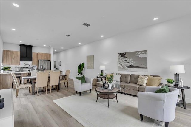 living room featuring light wood finished floors, visible vents, and recessed lighting