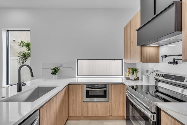 kitchen with custom range hood, modern cabinets, light stone countertops, stainless steel appliances, and a sink