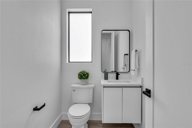 bathroom featuring baseboards, vanity, toilet, and wood finished floors