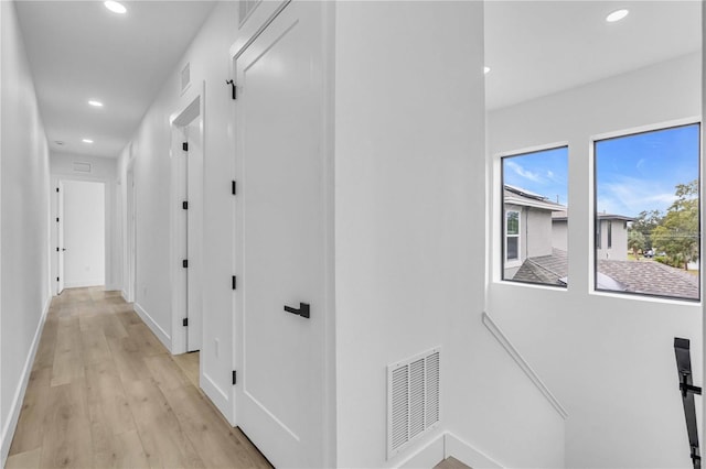 corridor featuring light wood-type flooring, visible vents, baseboards, and recessed lighting