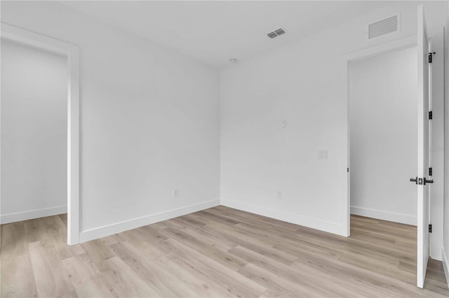 unfurnished room featuring visible vents, light wood-style flooring, and baseboards