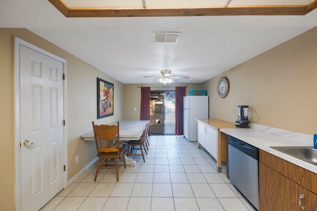 kitchen with visible vents, light countertops, freestanding refrigerator, dishwasher, and brown cabinetry