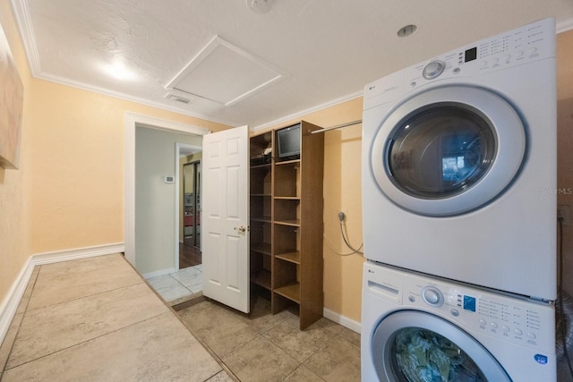 washroom featuring laundry area, ornamental molding, stacked washer and clothes dryer, and attic access