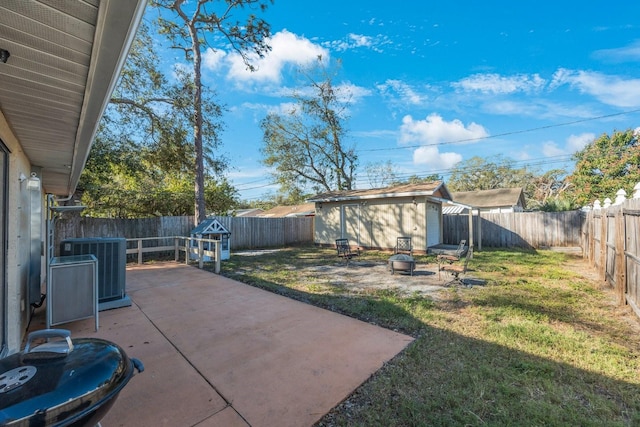 view of yard featuring an outbuilding, a patio, central AC unit, a fenced backyard, and a fire pit