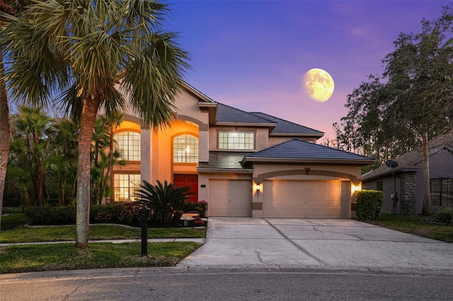 view of front of home with concrete driveway, a tiled roof, a garage, and stucco siding