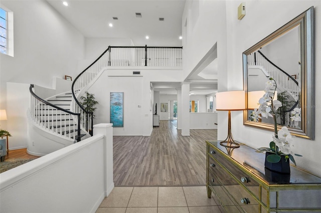 foyer with wood finished floors, recessed lighting, stairway, a high ceiling, and baseboards