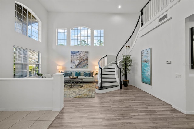 foyer with wood finished floors, recessed lighting, a high ceiling, baseboards, and stairs