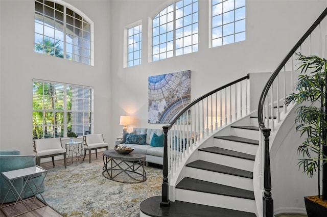 stairs featuring a towering ceiling and wood finished floors