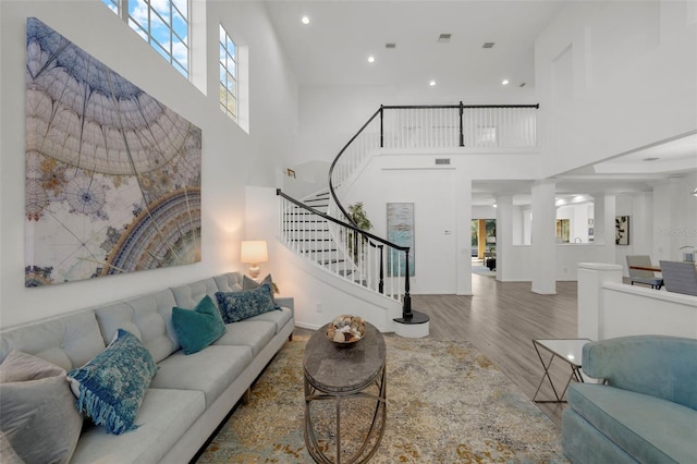 living room with stairway, recessed lighting, wood finished floors, and a high ceiling